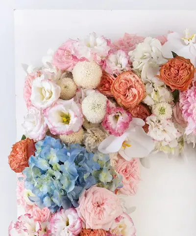 รายละเอียดดอกไฮเดรนเยียสีฟ้า กุหลาบชมพู และดอกไม้สีขาวบนพวงหรีดดอกไม้สด