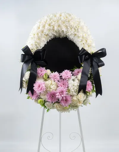 พวงหรีดดอกไม้โทนขาวชมพู ทรงวงกลม ประดับโบว์สีดำ