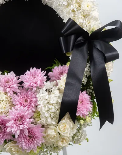 รายละเอียดดอกไม้โทนชมพูขาวและโบว์สีดำบนพวงหรีด