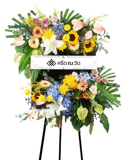 พวงหรีดกระดานดอกไม้สดหลากสี จัดด้วยลิลลี่ขาว ทานตะวัน ไฮเดรนเยียฟ้า เยอบีร่าสีน้ำตาลส้ม มัมปิงปองเหลือง ใบจั๋ง ใบฟิโลเดนดอน
